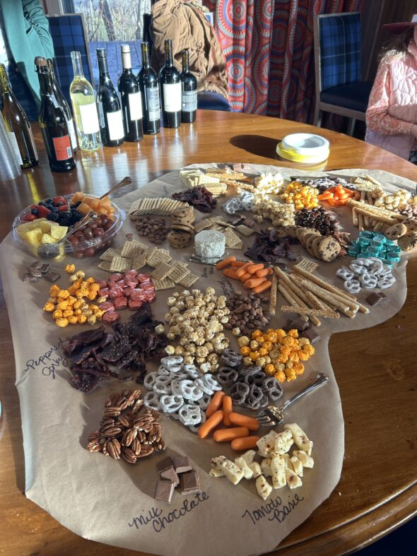 charcuterie spread on table with nuts, cheese, fruit, chocolate